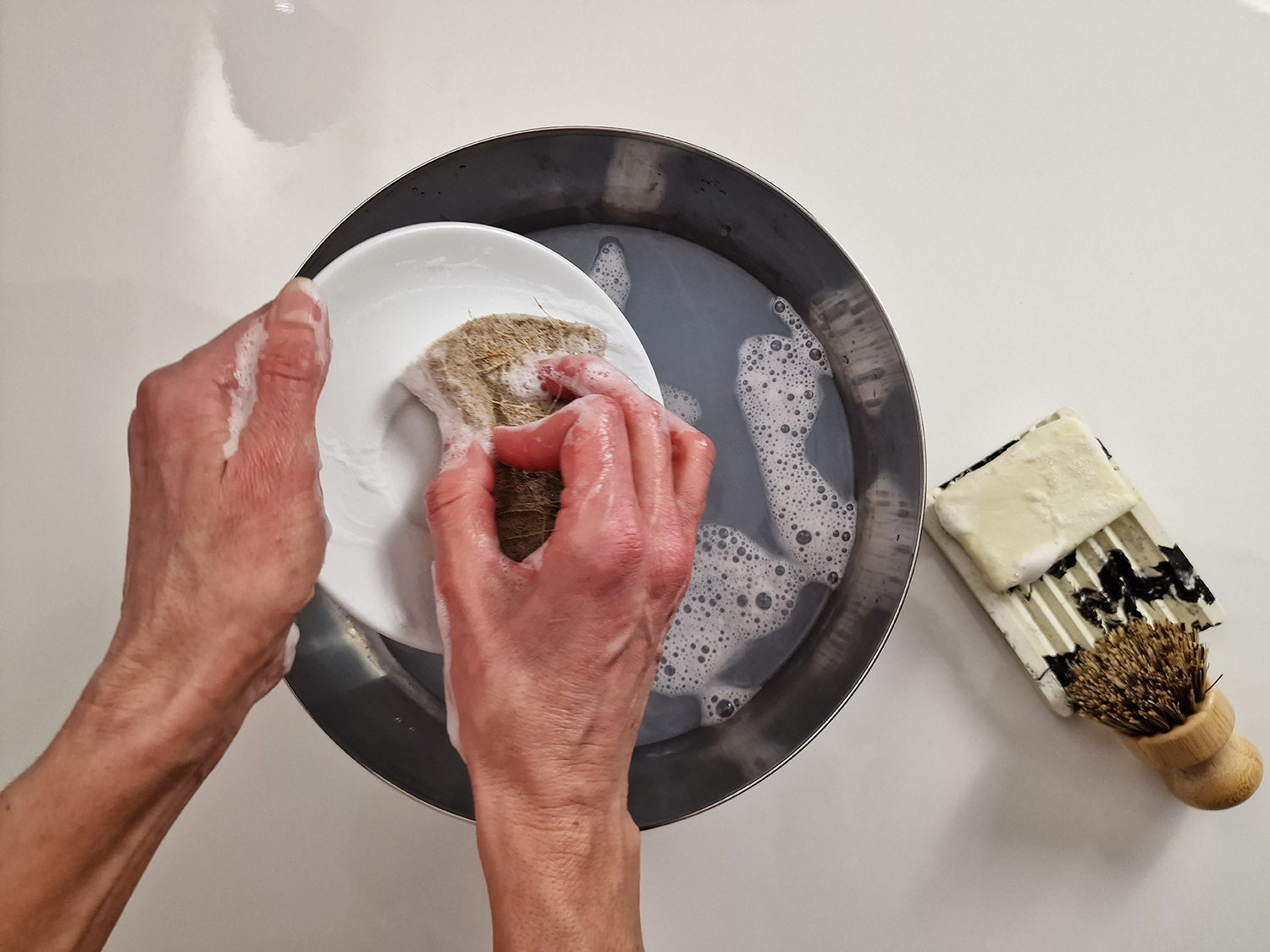 Vierka lava los platos utilizando un jabón sólido para lavar platos que ella misma elaboró con materias primas de Handymade.